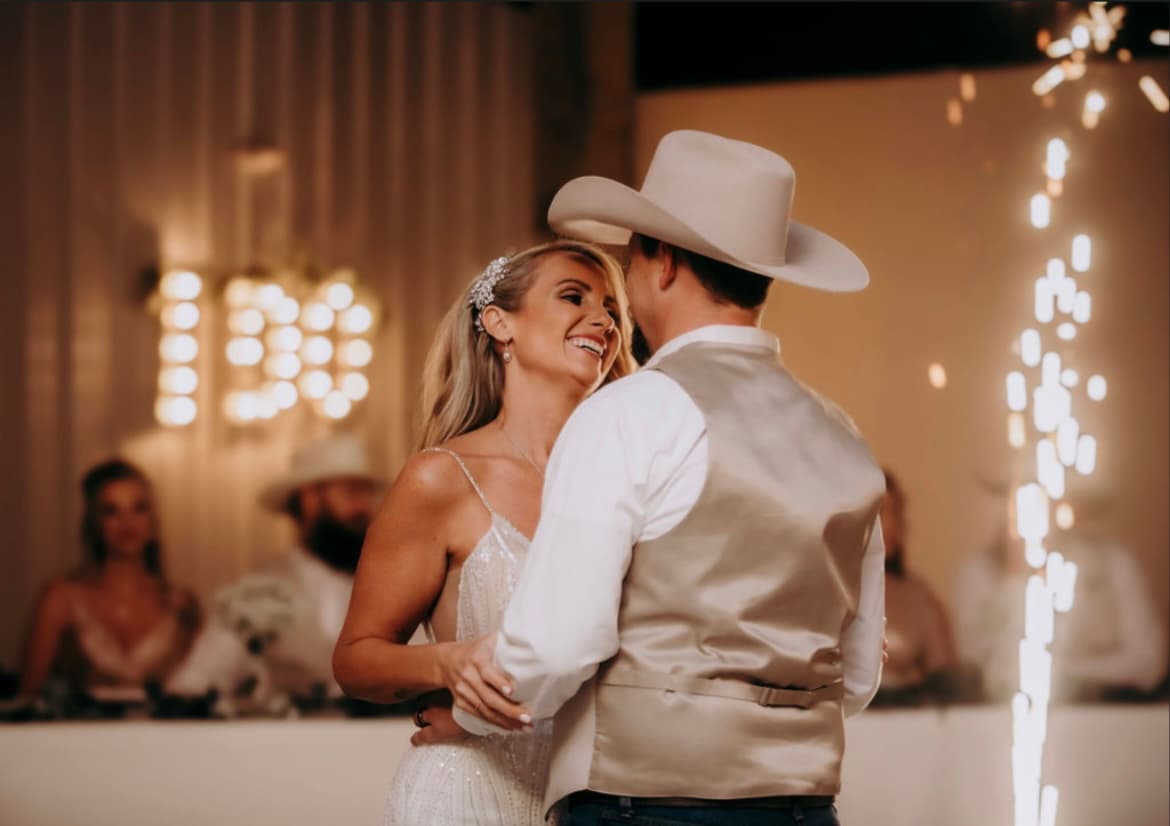 First dance on the dance floor beneath a bulb-lit I DO sign